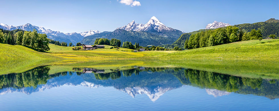 Austrian Alps with green hills and a lake in the foreground