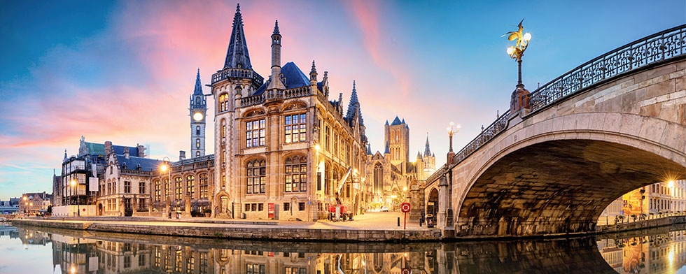 Ghent bridge and spired buildings lit up at sunset